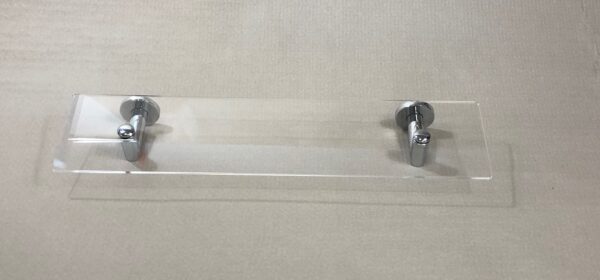 Repisa de metacrilato transparente Carena Brillo con soportes cromados, instalada en la pared de un baño
